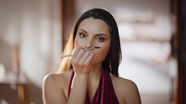 Göz kamaştırıcı bir kadın kirpiklerine maskara sürüyor. Ev aynasıyla yakından bakıyor. Makyaj yapan güzel bir kadın gözlerine makyaj malzemesi sürüyor. Dairendeki romantik buluşmaya hazırlanan göz kamaştırıcı model..