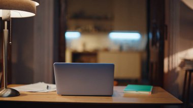 Laptop, lamba lambasının yanındaki boş daire boş duruyor. Konforlu akşam çalışma alanındaki ahşap masaya yerleştirilmiş açık bilgisayar. Çevrimiçi dijital çalışmaya hazır uzak bir işyeri. Serbest konsept.