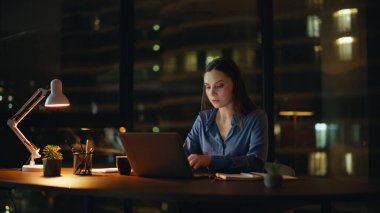 Kadın yönetici gece geç saatlere kadar çalışıyor. Ciddi bir iş kadını karanlık bir iş yerinde lamba ışığında dizüstü bilgisayar yazıyor. Fazla mesai yapan bayan çalışanlar fazla mesai yapmayı düşünüyor. İşçi aşırı yüklenmesi.