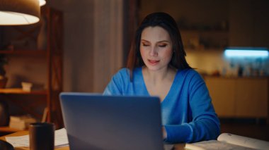 Yaratıcı yönetici video araması, projeyi açıklamak için karanlık eve yakın çekim. Gece evinde dizüstü bilgisayarla konuşan gülümseyen bir kadın. Pozitif esmer uzaktan kumandalı bir ofiste çevrimiçi konferans veriyor.