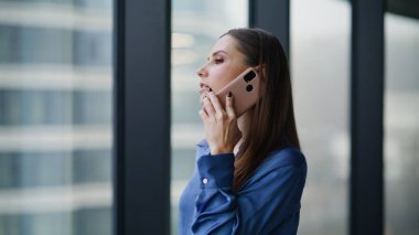 Profesyonel yönetici, ofis penceresine yakından bakarak akıllı telefondan danışmanlık yapıyor. Güzel bir iş kadını şirket binasında cep telefonunu arıyor. Kendine güvenen bayan çalışan konuşuyor..