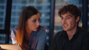 Akşam ofis kapanışında iki girişimci takım çalışmasını tatmin etmek için iş birliği yapıyor. Gülümseyen kadın iş arayan dizüstü bilgisayarlı tableti tartışıyor. Neşeli meslektaşlar birlikte yaratıcı bir başlangıç planlıyorlar..