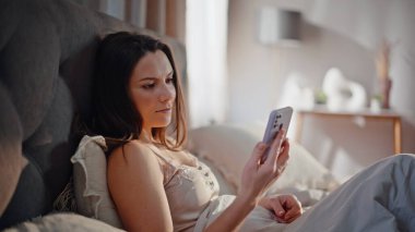 Hayalperest kadın rahat yatağında oturmuş güneşli bir sabahın erken saatlerinde akıllı telefon mesajı alıyor. Gülümseyen kadın cep telefonuyla ev odasında dinleniyor. Mutlu esmer, evde kaygısız hisseden mesajları okuyor..