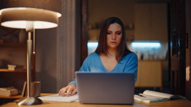 Geç saatte muhasebeci gazeteleri gözden geçirip akşam evde not tutuyor. Ciddi kadın uzaktan kumandalı yönetici dizüstü bilgisayar arıyor. Lamba ışığında çalışan profesyonel iş kadını.