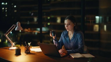 Karanlık apartman işyerinde online çalışan çalışkan bir serbest çalışan. Gece ofisinde dizüstü bilgisayar okuyan meşgul bir kadın. Fazla mesai müdürü elinde kahve fincanı tutuyor..