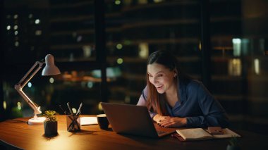 Mutlu Bağımsız Karanlık Ev İş Yeri 'nde video görüşmesinin tadını çıkarın. Gülümseyen iş kadını internet görüşmesini bitirdi ve laptop web kamerasına veda etti. Neşeli kadın çalışanın gülen videosu gece ofisinden arıyor.