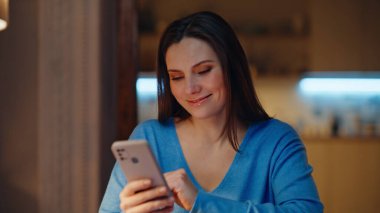 Happy Freelancer karanlık bir odada cep telefonu mesajı alıyor. Gülümseyen iş kadını akşam apartmanında oturmuş akıllı telefon mesajları okuyor. Neşeli kadın cep telefonuyla online alışveriş yapıyor..