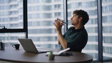 Yönetici ofisteki hoparlörde konuşan sanal ses tanıma asistanı kullanıyor. Kendine güvenen iş adamı cep telefonuyla sesli mesaj kaydediyor. Başkan hoparlörden konuşuyor.