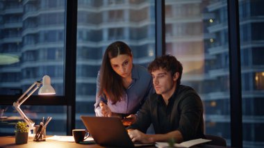 Ofis koçu, karanlık çalışma alanı için fazla mesai müdürüne yardımcı oluyor. Kadın patron tablet gösteren ciddi bir çalışana iş vazifesini açıklıyor. İki meslektaş aygıtlardaki pazarlama verilerini tartışıyor.