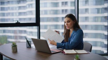 İnternetteki toplantıda yaşanan idari tartışmalar panoramik ofisteki iş sözleşmelerinin bozulmasına yol açtı. Sinirli iş kadını bilgisayar kamerasına kağıtları gösteren bir video görüşmesinde tartışıyor. Gergin kadın sanal sohbeti bitirdi.