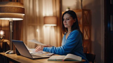 İş kadını, karanlık işyerinde gazete okuyor. Yakın plan. Gülümseyen kadın muhasebeci, dizüstü bilgisayarında lamba ışığında oturan belgeleri tatmin etti. Mutlu bayan serbest yazar, akşam üzeri online proje yapıyor..