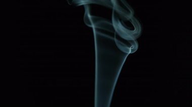 Duman halkalarının izleri nazikçe yükseliyor. Derin odak noktasından sonra mumdan süzülüyor. Karanlık stüdyo sessiz ve hareketsiz kalıyor. Siyah sahne ayini ve ruhani yansıma. Akışkan hareket