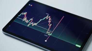 Değişen borsa eğilimleri ve büyüme göstergeleriyle birlikte canlı finansal grafiğini gösteren dijital tablet modern ofis masasında duruyor. Taşınabilir cihaz ekranında engelleme zinciri istatistiği. Finans simgeleri