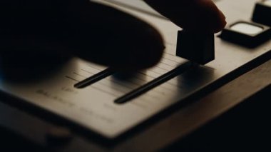 Ses mühendisi vintage ses kayıt cihazında kaydırıcıları kapatıyor. Tanımlanamayan adamın eli retro ekipmanlarda ses düzenleyicisini ayarlıyor. Klasik ses konsolu üzerinde profesyonelce çalışıyoruz. Eski moda.