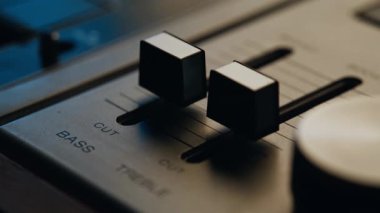 Profesyonel stüdyoda eski model ses kaydedicilerde Macro view faders. Kapalı baslı üçlü kaydıraklar içerideki retro müzikal konsolda sabit duruyor. Yumuşak ışık altında eski tarz kayıt ekipmanları paneli. 