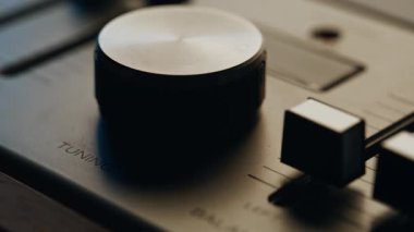 Sessiz stüdyodaki klasik müzik setinin ayar düğmesi. İçerideki retro müzik aletinin dengesini ayarlamak için makro görünüş elle kumanda ekipmanı. Metal yüzey, nostaljik sessizlikte sönmüş ışığı yansıtıyor..