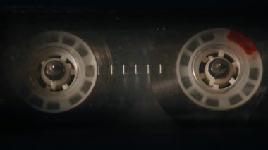 Vintage güverte yakın çekim yüklü dönen makaralı ses kaseti. Kapalı mekanda retro müzik çalan klasik manyetik kaset. Eski usul analog ses aygıtı melodi çalıyor. Eski tarz.