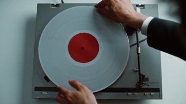 Eller, eski gramofona vinil disk yerleştiriyor. Masanın yakın planına yerleştiriliyor. Top view tanınmayan klasik müzik dinleyicisi retro plağı açıyor. Klasik çalgıcıdaki iğne basma düğmesini ayarlayan adam.