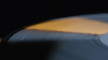 Kapanış plağı siyah arkaplanda dönüyor. İçerideki klasik müzik ekipmanlarıyla dönen Macro view grobeloved diski. Klasik turntable akşam ışığında retro melodi çalıyor. Eski tarz konsept.