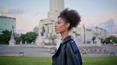 Mutlu gezgin tasasız hafta sonu kapanışında kasaba bölgesini keşfediyor. Gülümseyen Afrikalı Amerikalı kadın şehir meydanında tek başına tatilin tadını çıkarıyor. Güzel bir bayan Deri ceket giyerek şehirde geziniyor