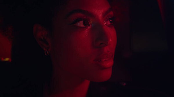 Расслабляющий пассажирский автомобиль в ночном городе освещенный неоновые огни крупным планом. Портрет привлекательной африканской женщины, сидящей на заднем сиденье автомобиля. Серьезные дамы наслаждаются поздним вечером поездки в авто.