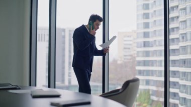 Modern ofisteki cep telefonu konuşmasında bir yönetici şikayette bulunmuş. Sinirli iş adamı panoramik pencerenin yanındaki belgeleri telefonla tutuyor. Stresli müdür kağıt hatasını tartışıyor.
