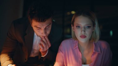 İki çalışan gece yarısı karanlık ofiste proje bütçesi için birlikte çalışıyorlar. Ciddi bir iş adamı tabletteki istatistik verilerini kadın CEO 'ya gösteriyor. Çözüm arayan çalışkan meslektaşlar