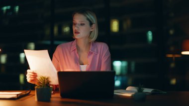 Profesyonel muhasebeci gece geç saatlerde lamba ışığında evrak işlerini hallediyor. Ciddi bir iş kadını, gece ofisinde strateji üzerine finansal istatistiksel düşünce içeren belgeler okuyor. Sarışın fazla mesai yapıyor..