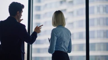 Gülümseyen iş arkadaşları panoramik pencere önünde konuşurken şirket binasını kapatıyorlar. Pozitif erkek ofiste zarif bir bayanla flört ediyor. Neşeli meslektaşlar şehir manzaralı haberleri tartışıyor..