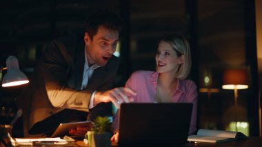 Başarılı iş arkadaşları birlikte başarının tadını çıkarıyor. Gece şirketinin kapanış bölümünde dizüstü bilgisayar ekranına bakıyorlar. Gülümseyen meslektaşlar iş başarısını tartışıyor. Mutlu insanlar büyük finansal sonuçlara seviniyor..