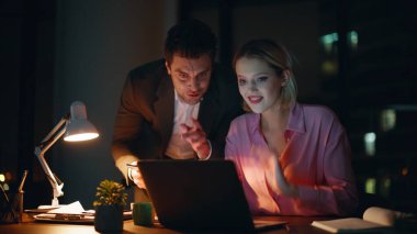 Yaratıcı girişimciler karanlık ajans ofisindeki projede iş birliği yapıyorlar. Tablet memnun takım çalışması verilerini tartışan iş adamlarına ilham kaynağı oldu. Gülümseyen meslektaşlar akşam birlikte çalışıyorlar..
