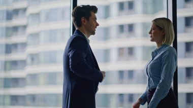 Başarılı iş adamları ofis panoramik penceresinden el sıkışıyor. İki kendine güvenen yönetici modern şirket içinde selamlaşıyor. Gülen ortaklar kapalı alanda yapılan görüşmelerden sonra el sıkışıyor.