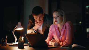 Aşırı yüklü iş arkadaşları gece iş yerinde sorunları birlikte çözüyorlar. Ofis belgelerinde iş verilerine bakan endişeli meslektaşlar. Çalışkan yöneticiler birlikte projeyi tartışıyorlar.