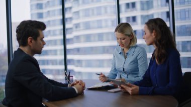 Modern ofiste sözleşmeyi tartışan ciddi profesyoneller. Gülümseyen meslektaşlar şirket toplantısında proje detaylarını görüşüyorlar. İş ortakları panoramik iş yerinde el sıkışıyor.