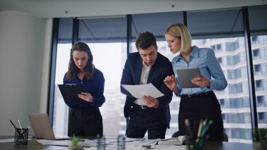 İş ortakları iş yeri yaratıcı ajansında etkileşim halindeler. Profesyonel yöneticiler kağıt tabletinde mali verileri tartışarak beyin fırtınası yapıyorlar. Üç meslektaşım birlikte pazarlama stratejisi üzerinde çalışıyor..