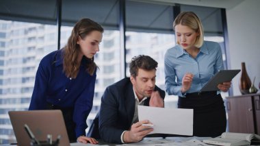 Şirket ekibi modern ofis çalışma alanının yakın çekimlerinde gazete okuyor. Üç takım arkadaşı pazarlama stratejisini tartışıyor ve verileri bilgisayara giriyorlar. İş projesinde birlikte çalışan grup arkadaşları.