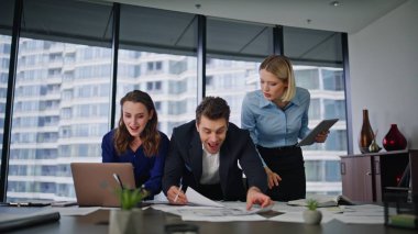 Mutlu ekip, şirket ofisinde başarılı bir takım çalışmasının keyfini çıkarıyor. Üç meslektaş iş yerinde iş başarısını kutluyor. Gülümseyen iş arkadaşları iş başarılarını kutluyor..