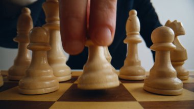 Oyuncuların parmakları satrancı rekabete yakın çekimde kaydırıyor. Mantık yarışması tahtası. Oyun alanındaki isimsiz erkek el kontrol figürleri kapalı alanda. Kurumsal düşünür akıllıca taktik stratejisi uyguluyor.