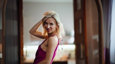 Yakın plan, ince kadın uzun romantik elbisesiyle ayna yansıması yapıyor. Güneşli evde seksi kız saç stili planlama akşam kıyafetine dokunuyor. Çekici model güzelliği takdir ediyor. Modadan hoşlanan bayan 