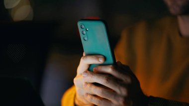 Gece evde elinde akıllı telefon tutan yakın çekim adamı. Portre gülümseyen işadamı cep telefonundan iyi haberler okuyor karanlık ofis işyerinde oturuyor. Mutlu serbest çalışan telefon maaş bildirimi alıyor.