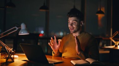 Gece vardiyasında çalışan danışman video lambanın ışığını kapatıyor. Arkadaş canlısı iş adamı iş detaylarını akşam saatlerinde online toplantıda tartışır. Profesyonel yönetici ofiste dizüstü bilgisayarla konuşuyor..