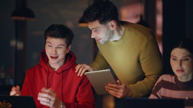 Ofis üyeleri karanlık işyerinde yakın plan konuşuyor. Yönetici, geceleri birlikte çalışan genç öğrencilere görevleri açıklıyor. Gülümseyen erkek müdür, akşam geç saatlerde kadınların elini sıkıyor..