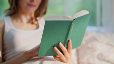 Odaklanmış okuyucu görünümlü kitap ilginç bir hikayeye yakından daldırıldı. Rahat kadın kitap okuyor rahat bir daire yatağında yatıyor. Mutlu esmer sayfa çevirme yatak odasında edebiyat hobisi.