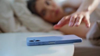 Uyuyan kadın aydınlık bir dairede uyanmaya çalışıyor. Genç esmer kadın cep telefonunu komodinin başından alıp alarmı kapatıyor. Rahat bayan akıllı telefon ekranına bakıyor, rahat bir yatakta yatıyor..
