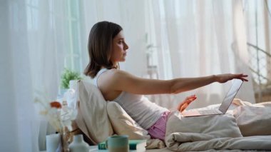 Yatakta dizüstü bilgisayarı kapatan kadın e-postayı sabah erkenden okumayı bitirdi. Sakin, güzel bir kadın dizlerinde bilgisayarla beyaz bir yatakta uzanıyor. Rahat esmer serbest çalışan rahat yatak odasında çalışıyor..