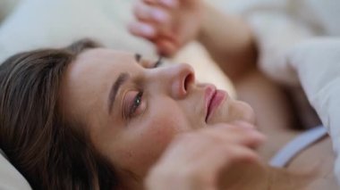 Kapalı bir kadın, yatak odasında uyanıyor. Sabahın erken saatlerinde baş ağrısı çeken genç ve uykulu bir bayan. Yorgun esmer, uykusuz hissediyor. Daire yatağında uyandıktan sonra tapınaklara masaj yapıyor..