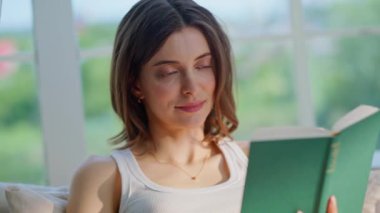 Rahat bayan, açık yatak odasının iç çekimlerinde romandan zevk alıyor. Kitap okuyan gülümseyen kadın rahat bir yatakta sabah kahvesini içiyor. Sakin genç esmer evde oturan ilginç edebiyata odaklanmış..