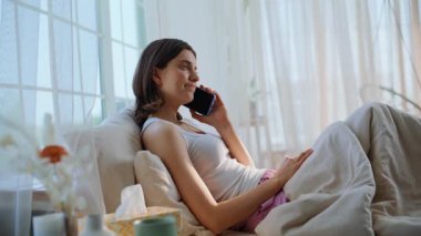 Hafif yatak odasındaki yastıklardan şikayet eden bir kadın. Hasta kadın, doktorla akıllı telefondan konuşuyor. Hastalık belirtilerini tartışıyorlar. Üzgün esmer konuşan cep telefonu yumuşak yatakta iyi hissetmiyor..