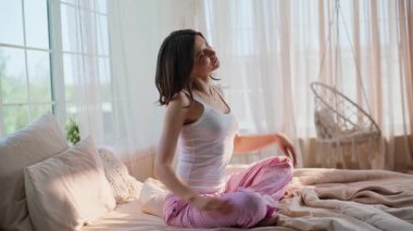 Sabah kızı, yumuşak yatakta bacak bacak bacak üstüne atmış bir şekilde oturuyordu. Kaygısız genç kadın erken uyandıktan sonra sağlıklı bir vücudu ısıtıyor. Güzel, fit esmer, yatak odasında günlük hayatın tadını çıkarıyor..