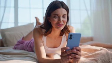 Cep telefonunda haber yayını yapan bir kız rahat bir şekilde ev yatağında uzanıyor. Rahatlamış esmer mesajlar, akıllı telefonlar yatak odasında dinleniyor. Tasasız kadın, hafta sonları internet üzerinden iletişim kurmaktan hoşlanıyor.